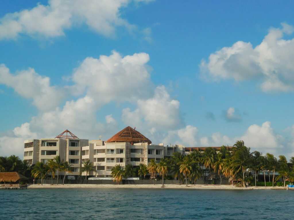 Luxury beachfront resort with palm trees and ocean view under a bright blue sky.