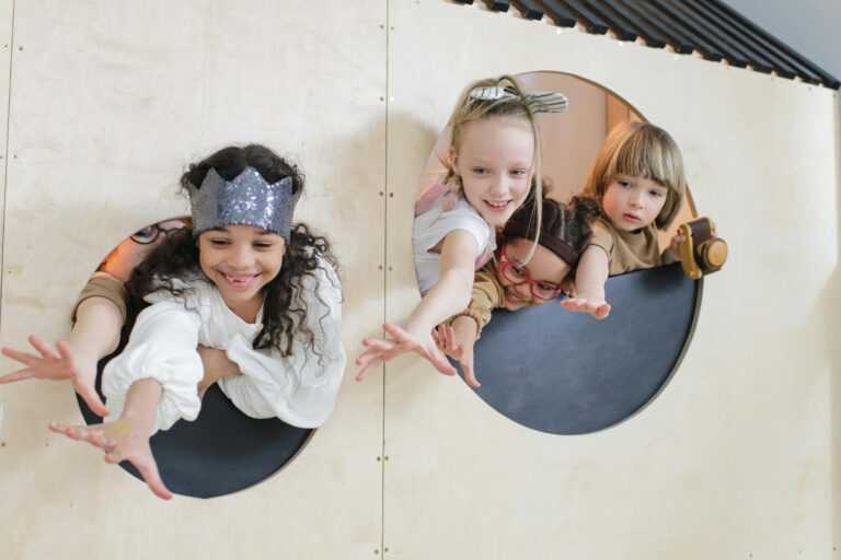 Children reach out joyfully in an indoor play setting. Captures innocence and diversity in play.
