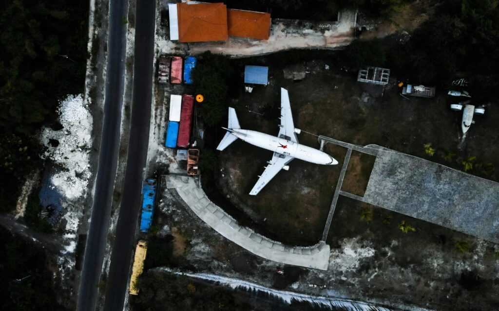 Aerial shot of an airplane in a Bali junkyard, showcasing industrial themes and vibrant colors.