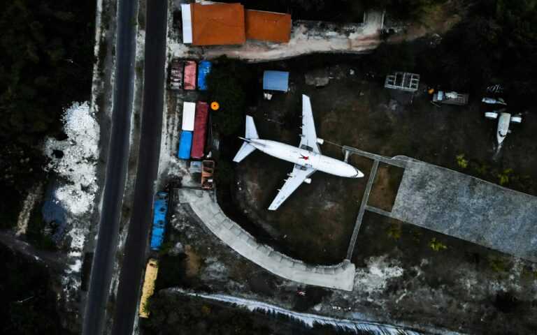 Aerial shot of an airplane in a Bali junkyard, showcasing industrial themes and vibrant colors.