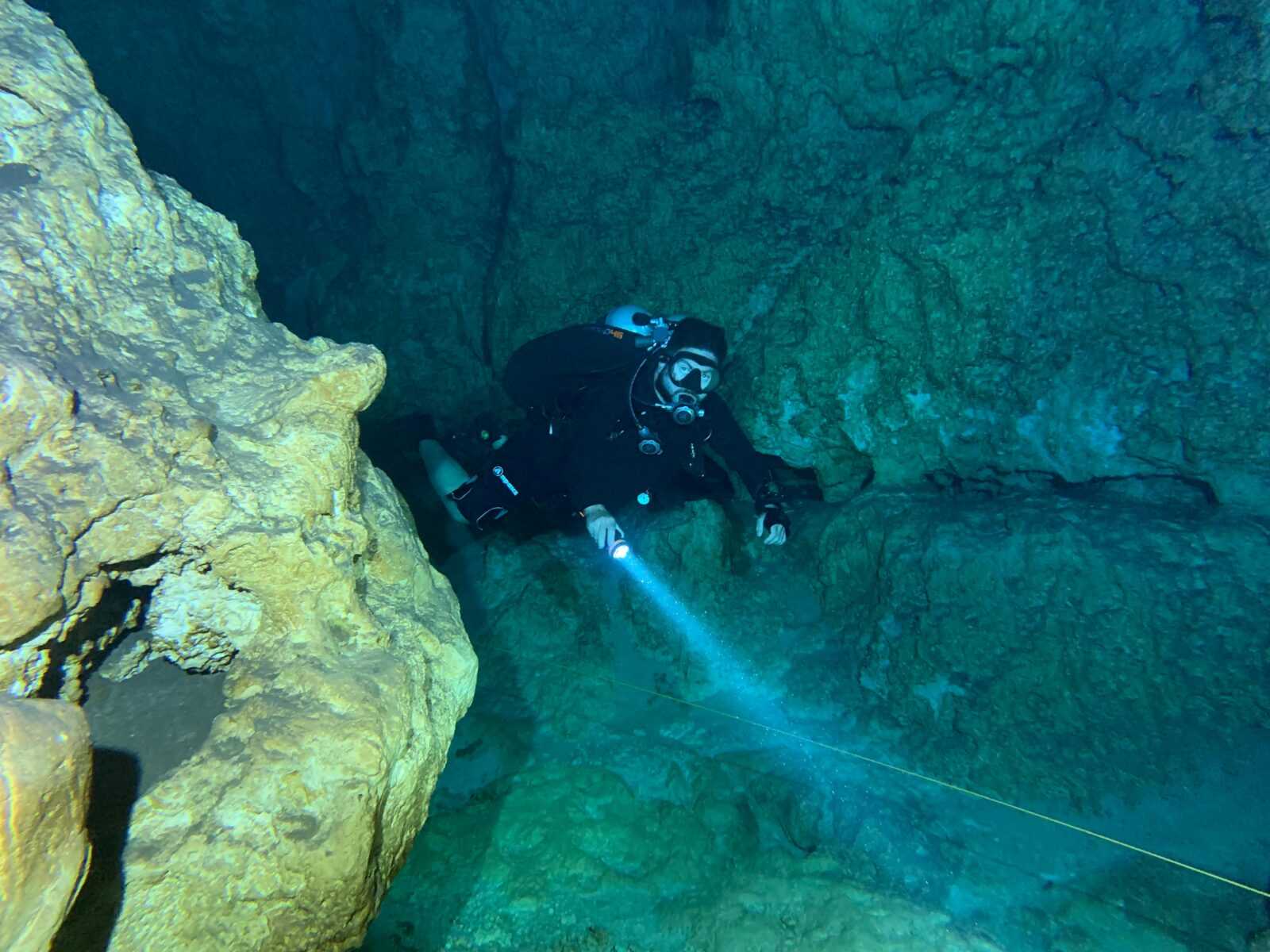 A diver exploring an underwater cave using a flashlight